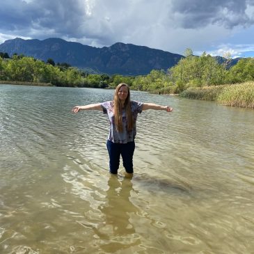 Brook Bhagat stands in a lake with her arms open wide