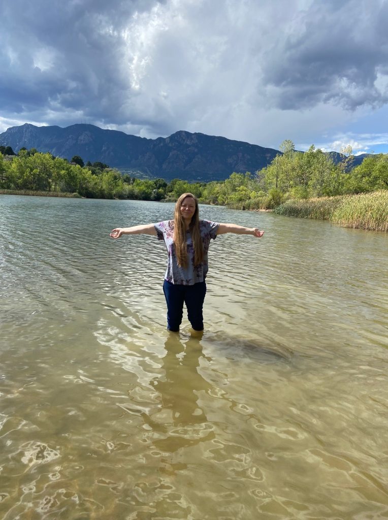 Brook Bhagat stands in a lake with her arms open wide